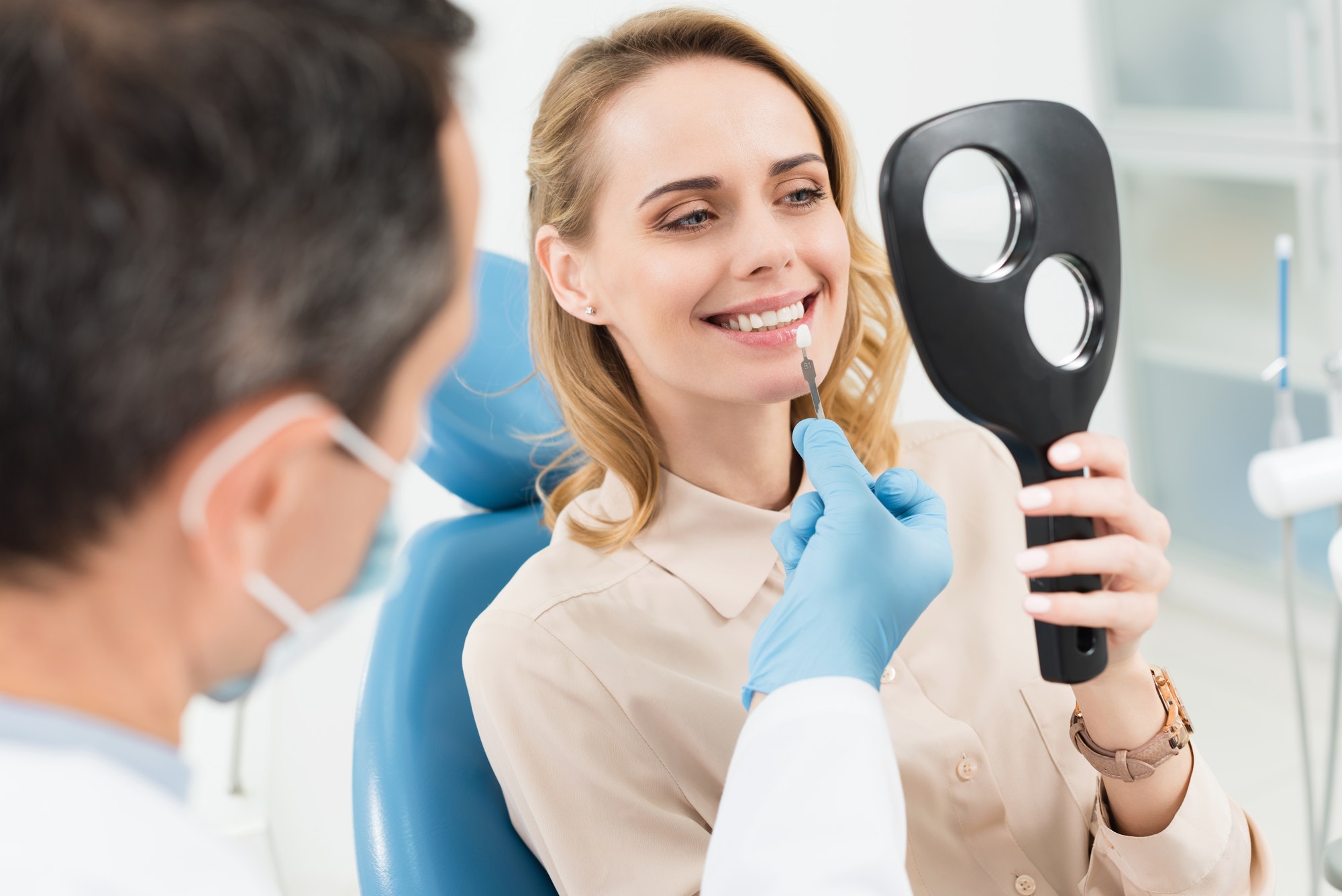 female-patient-choosing-tooth-implant-looking-at-mirror-in-modern-dental-clinic.jpg
